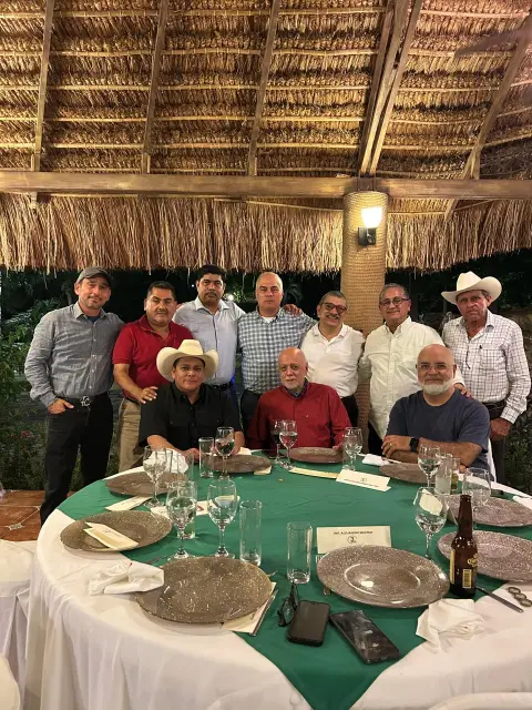 Asistentes reunidos en una de las mesas de la cena bajo la palapa